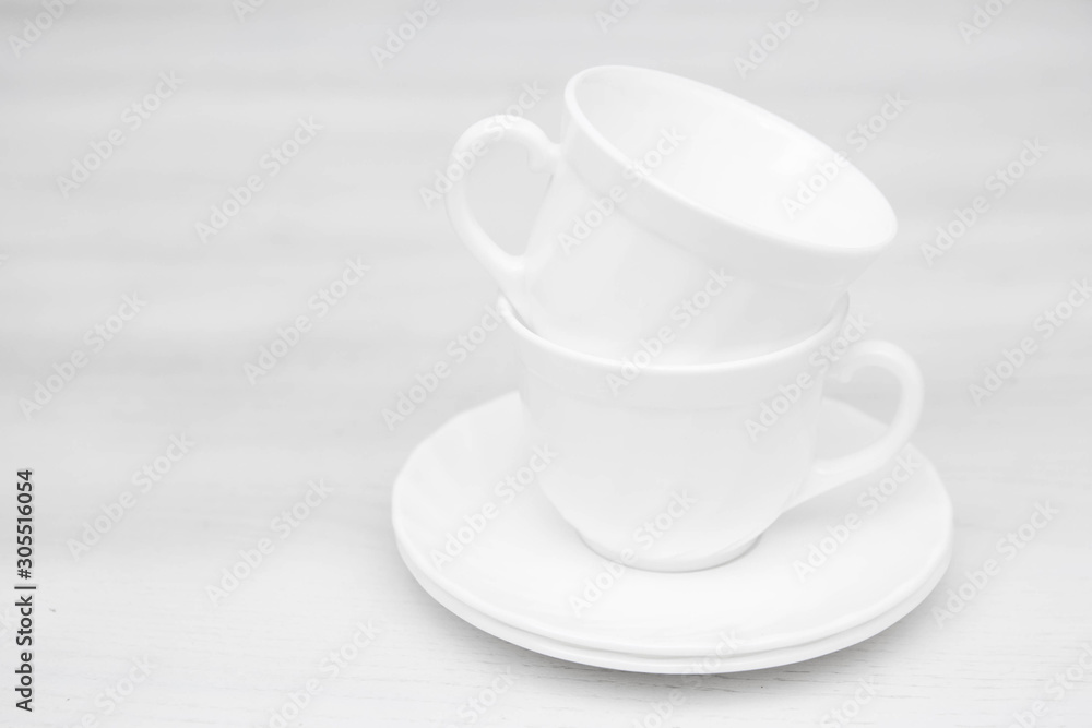 White ceramic cups with saucers on white table. Space for text White ceramic cups with saucers on white table. Space for text