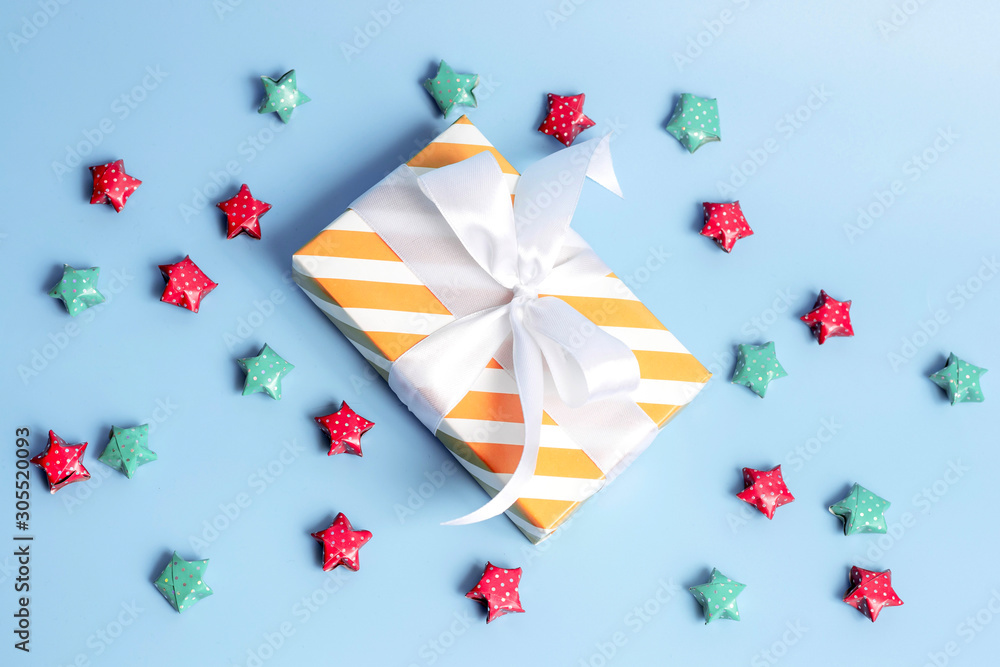 Gift box wrapped in kraft paper and multicolored stars on blue background. Top view, holiday concept. Gift box wrapped in kraft paper and multicolored stars on blue background. Top view, holiday concept.