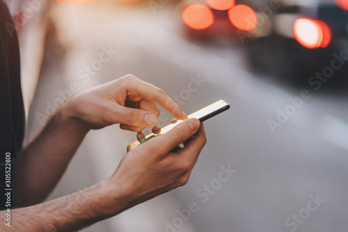 Business travel concept, Close-up of mans hands using smartphone on the street