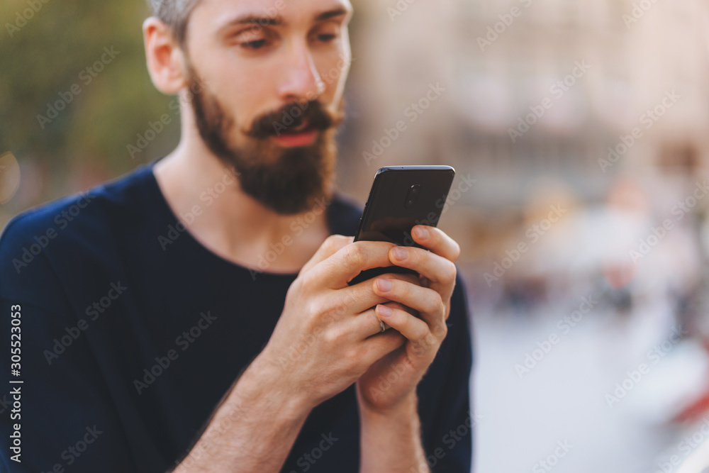 Influencer lifestyle concept, Side view shot of young smiling man using smartphone at the street Influencer lifestyle concept, Side view shot of young smiling man using smartphone at the street