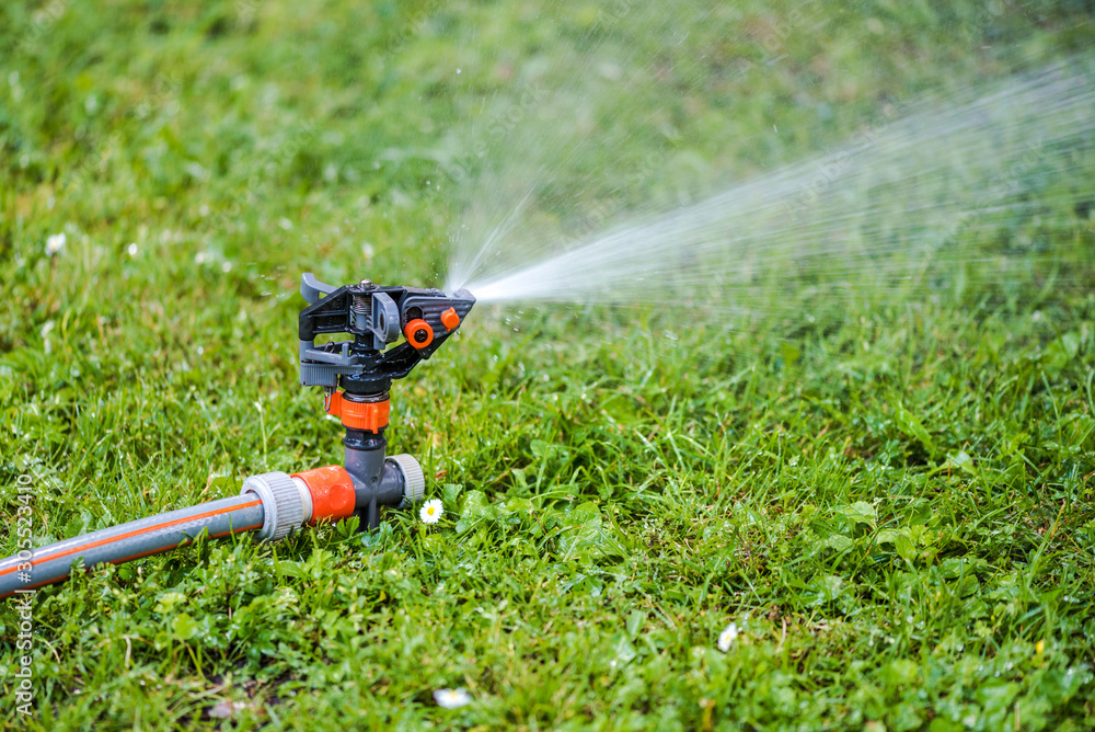 Naklejka premium Lawn sprinkler system and green grass meadow