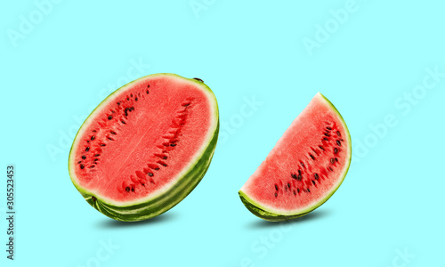 Green, striped watermelon, turquoise background with copy space for text, images. Cross-section. Berry, pink flesh, black seeds. Side view. Close-up.