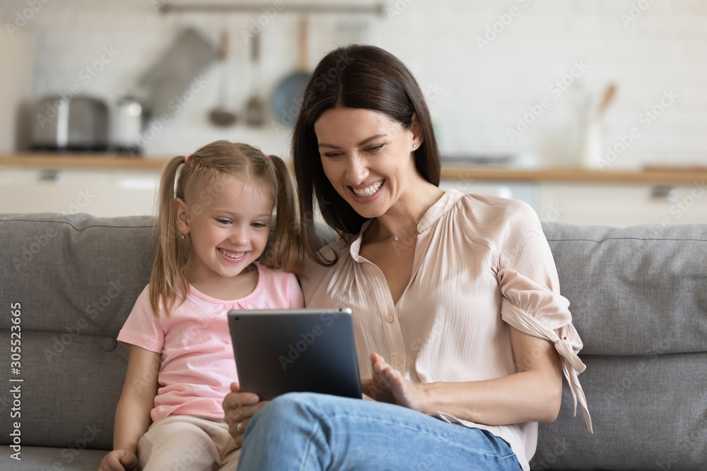 Cheerful mom with kid daughter using digital tablet at home Cheerful mom with kid daughter using digital tablet at home