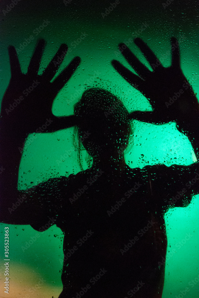 Silhouette of a single adult female through a water droplets on a green background