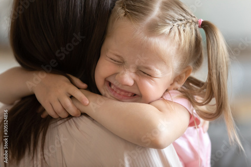 Funny cute little girl smiling embracing foster care parent mum