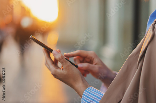 Close up image of female hand pointing finger on screen smartphone on background bokeh light in city center