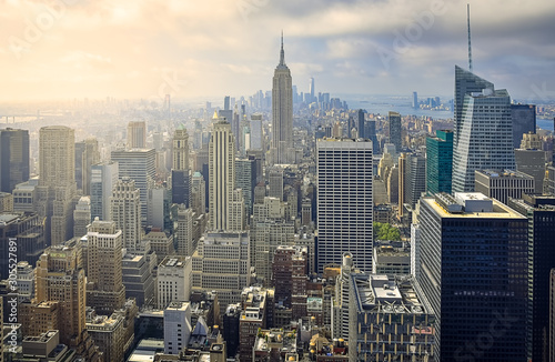 Iconic aerial view of New York City on a sunny day. Sunbeams between the skyscrapers, and cloudy background. Concept of travel. NYC, USA
