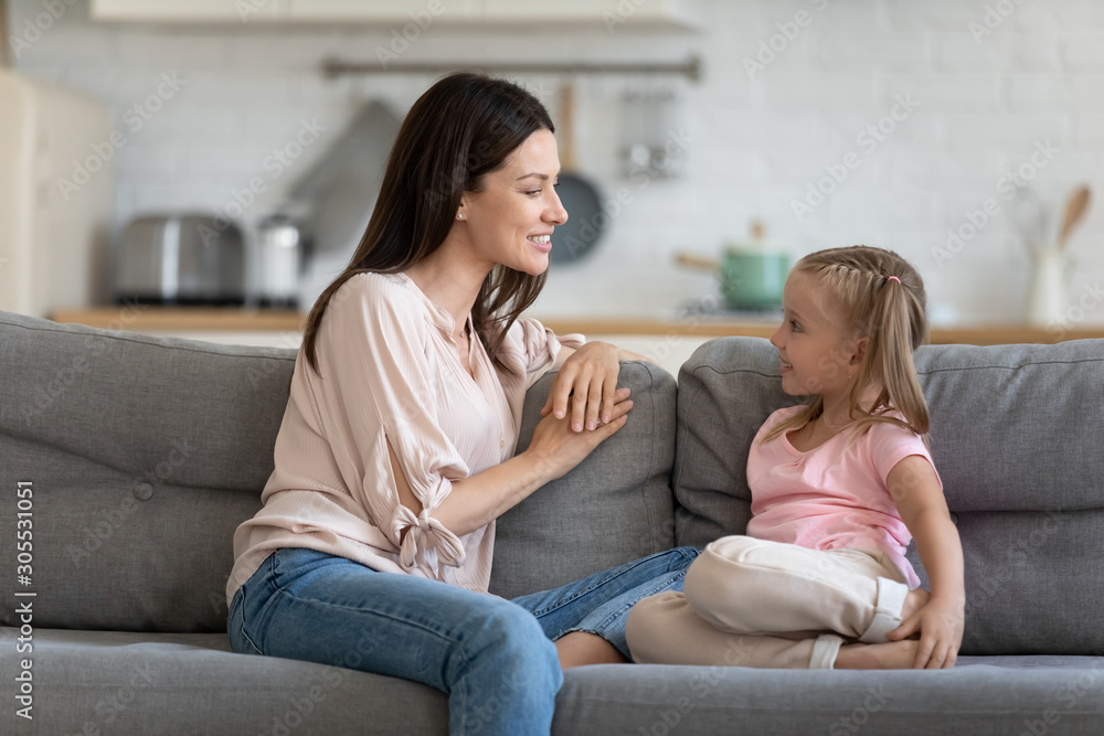 Happy mother and cute child enjoy talking relaxing on sofa