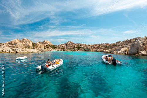 Unidentifiable tourists on small boats in an emerald water gulf - La Maddalena National Park - Parco Nazionale Arcipelago di La Maddalena photo