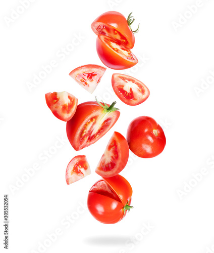 Whole and sliced fresh tomatoes fall down on a white background