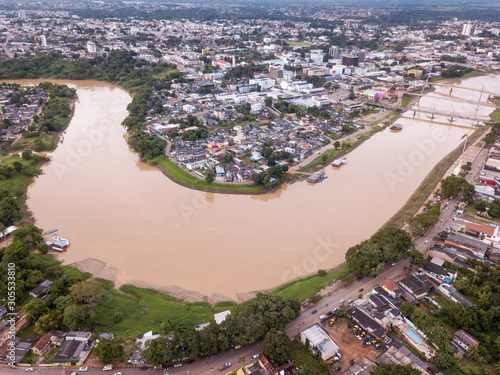 Aerial drone view of Acre river in the amazon and Rio Branco city center buildings, streets, bridges on cloudy winter day. Concept of environment, ecology, global warming, climate change and travel.