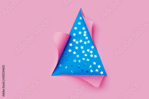 confetti in the form of stars in triangular Torn hole and ripped of paper in a shape of Christmas tree. Christmas flat lay