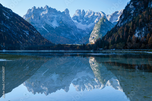 Autumn peaceful alpine lake Durrensee or Lago di Landro. Snow-capped Cristallo rocky mountain group behind, Dolomites, Italy, Europe. Seasonal and nature beauty concept. People and cars unrecognizable