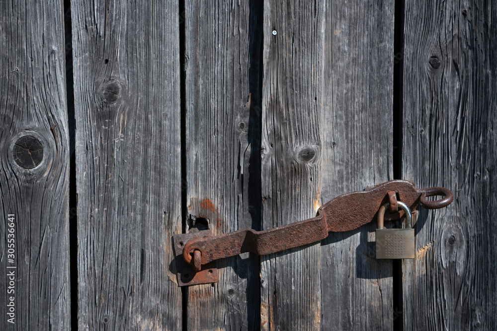 Detail of a rusty padlock at weathered wooden planks Detail of a rusty padlock at weathered wooden planks