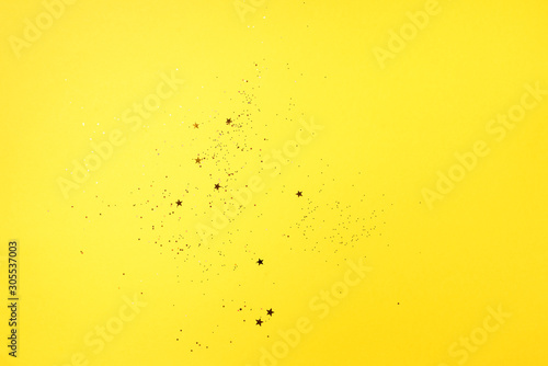 Golden star sparkles on yellow background. Christmas and New year concept. Festive backdrop with copy space © jchizhe