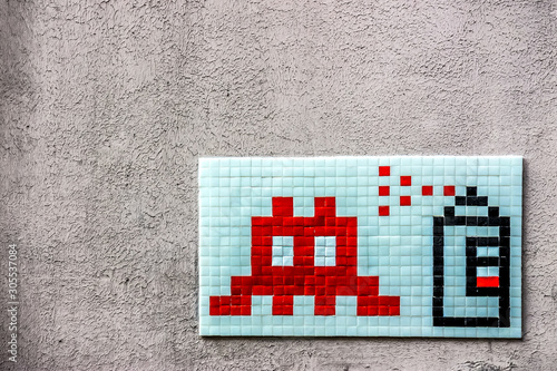 a graffiti mosaic depicting a spray can and an icon of space invaders on a wall of paris photo