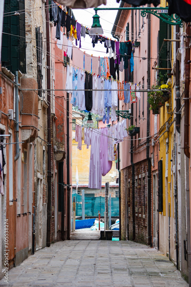 many clothes hanging on ropes in a narrow alley without people, a typical Italian scene in Venice, Italy