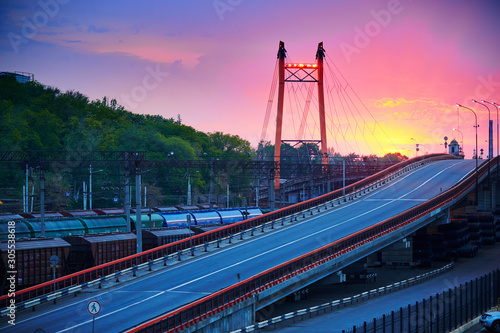 truck with container rides over the bridge, beautiful sunset, freight cars in industrial seaport, the road goes up