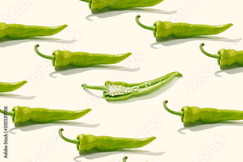From above creative composition of sliced green pepper with seeds among whole peppers on white surface