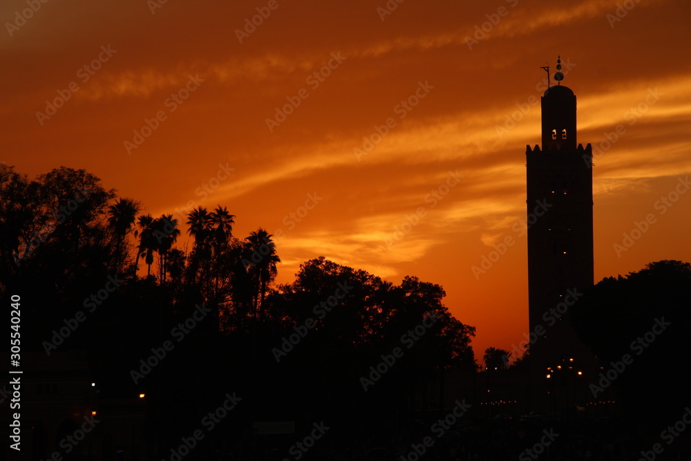 Orange sunset in the tower of the Marrakech square from a roof. Morocco