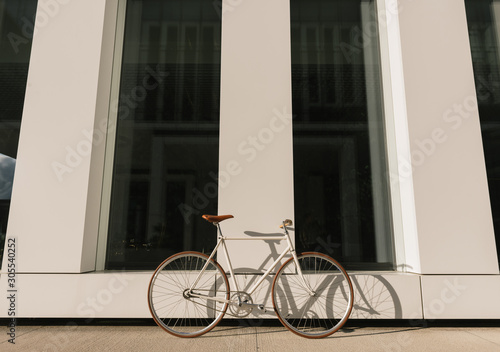 Bike parked on sidewalk near wall of contemporary building on sunny day on city street photo