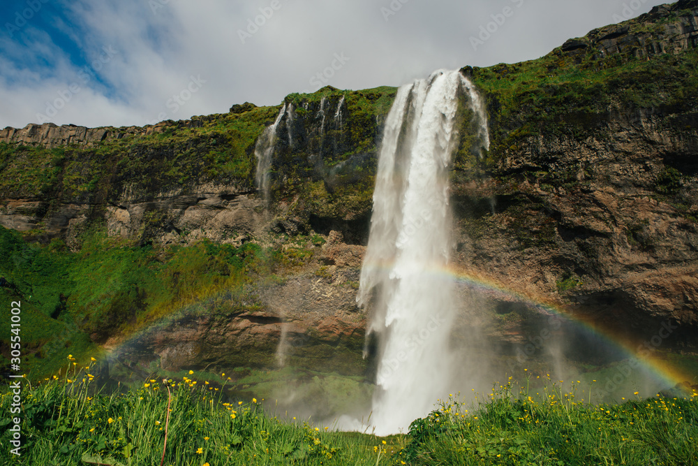 Breathtaking landscape of rainbow on background of foamy waterfall from mountain in bright day in Iceland Breathtaking landscape of rainbow on background of foamy waterfall from mountain in bright day in Iceland