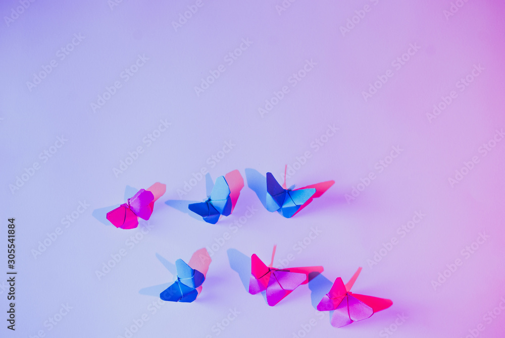 Pink and blue butterflies attached to lilac wall over carved paper leaf Pink and blue butterflies attached to lilac wall over carved paper leaf