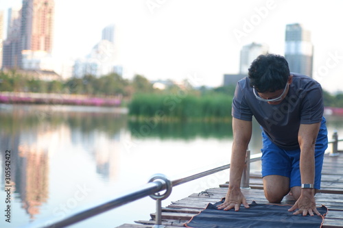 man on bridge​ doing flexible yoga exercise in the park in the evening