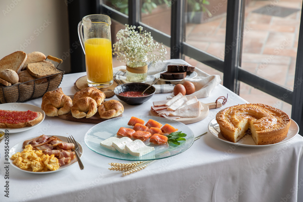 From above of appetizing sitting table for breakfast with bakery seafood sandwiches eggs and orange juice at stylish dinning room From above of appetizing sitting table for breakfast with bakery seafood sandwiches eggs and orange juice at stylish dinning room
