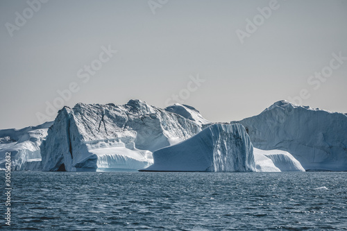 Floating iceberg in deep blue ocean water. Greenland and Antarctica. Global warming concept. Blue Sky and ice fjord.