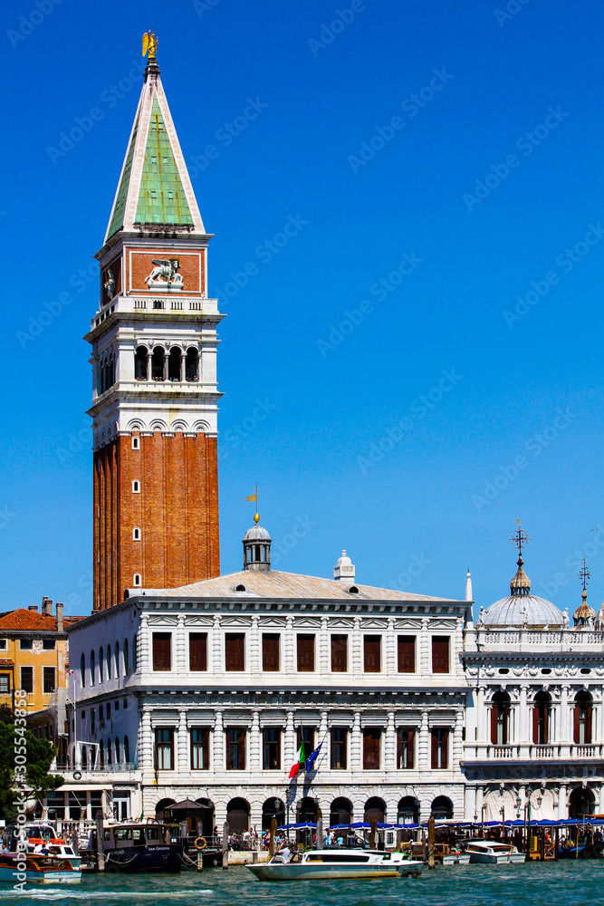 view of the bell tower of san marco seen from the sea of the lagoon full of boats and gondolas
