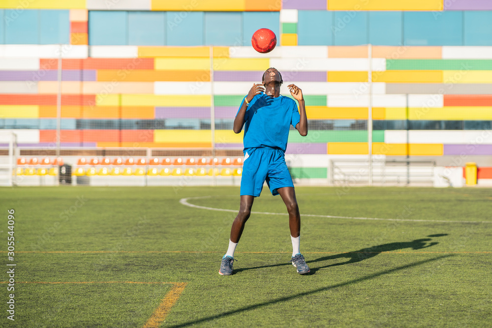 Skinny black teenager jugging football ball on head Skinny black teenager jugging football ball on head
