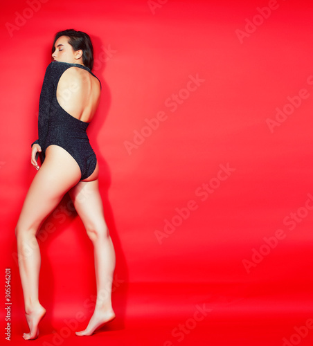 young pretty lady in shiny bodysuit posing on red background, lifestyle people concept