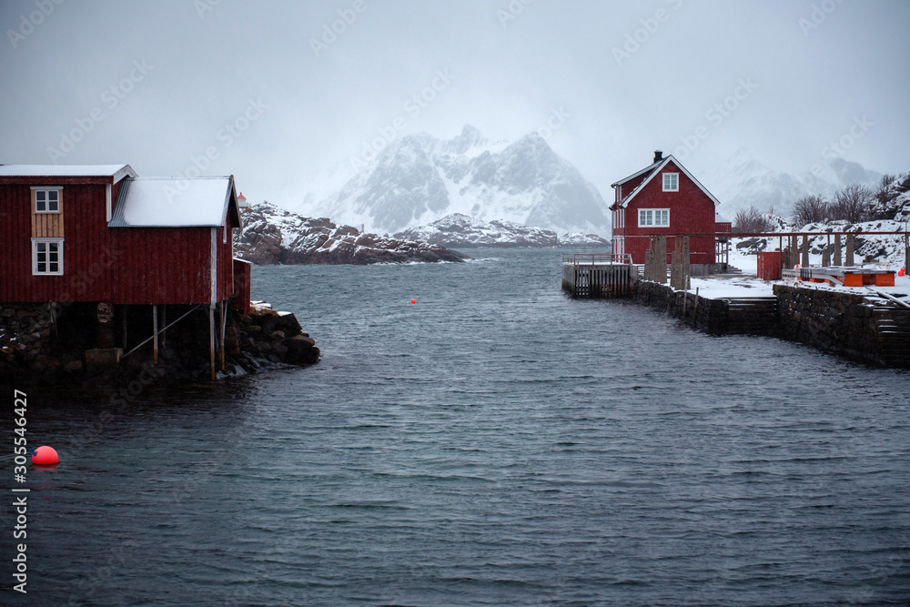 Lofoten, Norway. Beautiful red houses near the water, on the background of rocky snowy mountains