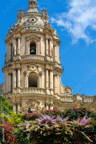 Front view of the Cathedral of San Giorgio on a summer day with colorful flowers in Modica, Sicily, Italy