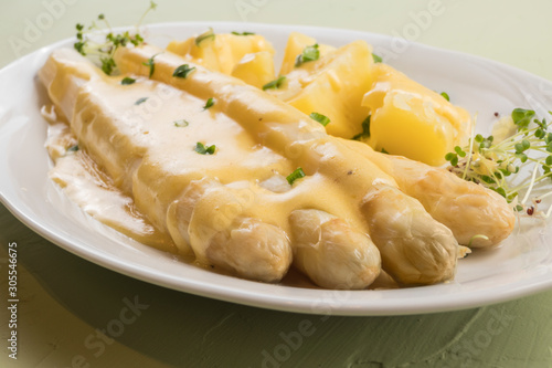 white asparagus poured with .hollandaise sauce, potatoes with chives and sprouts.