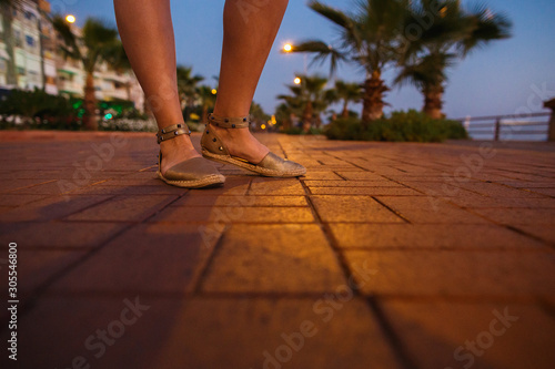 Woman legs in the dusk street of tropical city.