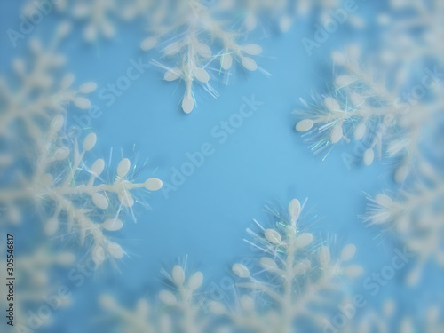 white plastic snowflakes made of shiny tinsel on a blue background. Christmas background. view from above. bokeh. center selective focus © Victoria ArtWK