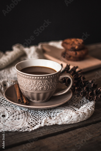 Hot coffee with cinnamon sticks and cookies on a wooden background © Tea