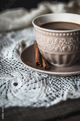 Hot coffee with cinnamon sticks on a wooden background
