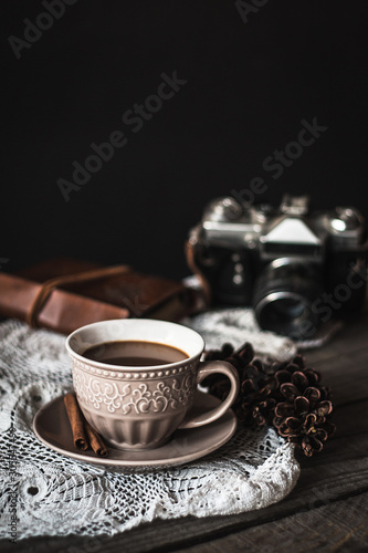 Hot coffee with cinnamon sticks, cookies and vintage camera on a wooden background