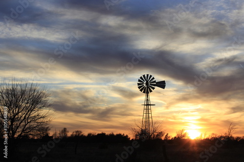 Windmill Silhouette at Sunset with a colorful sky out in the country.