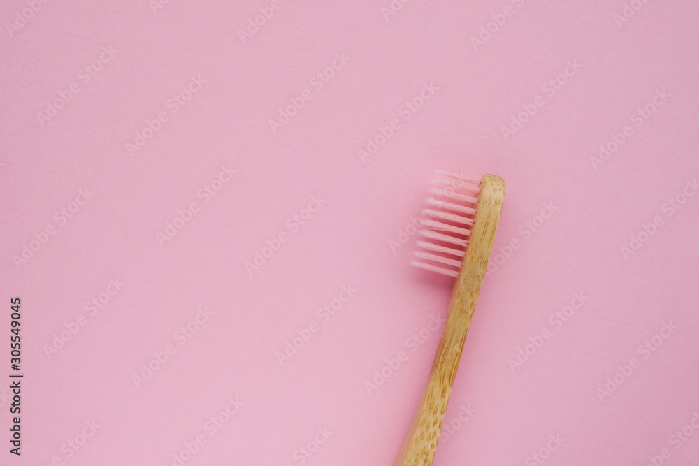 Stylish natural eco friendly toothbrush with wooden bamboo handle on pink background. Oral hygiene concept. Copy space. Flat lay, top view. Reduce plastic waste, sustainable lifestyle.