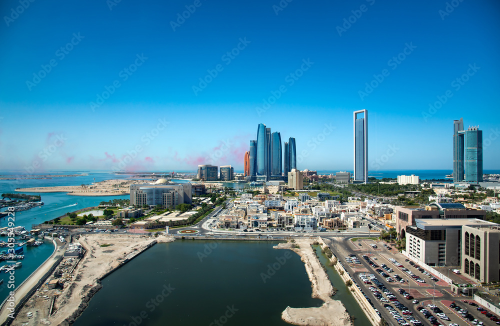 Abu Dhabi skyline with air show colors in the sky and view of the downtown modern buildings