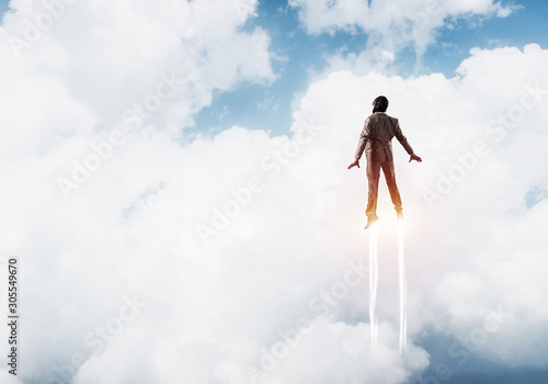 Obraz na płótnie Businessman in suit and aviator hat flying in sky w salonie