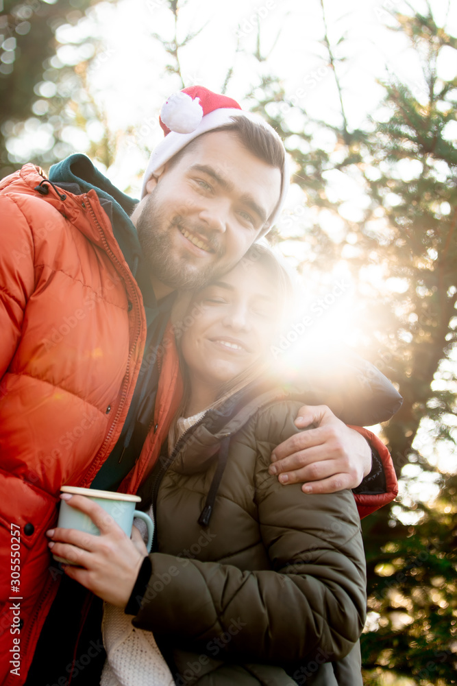 Romantic couple in Christmas hats near fir tree. Romantic couple in Christmas hats near fir tree.