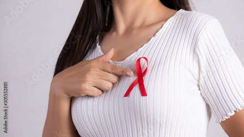 Wallpaper Mural Closeup of woman hand pointing to red badge ribbon on chest to support AIDS Day. Healthcare, medicine and AIDS awareness concept. Torontodigital.ca