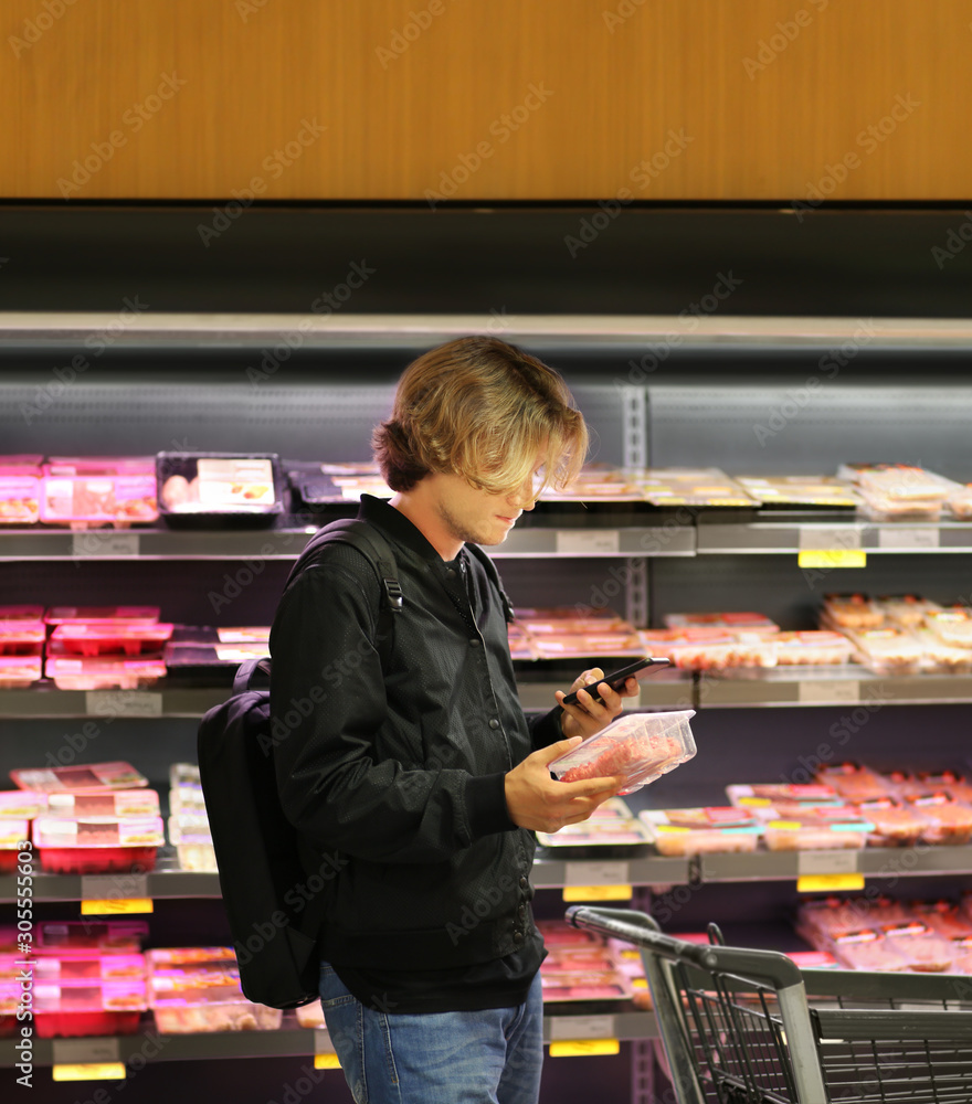 man purchasing a packet of meat at the supermarket
