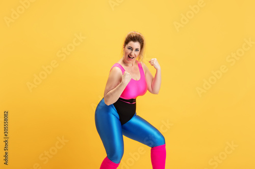 Young caucasian plus size female model s training on yellow background. Copyspace. Concept of sport  healthy lifestyle  body positive  fashion  style. Stylish woman posing like superhero  girl power.