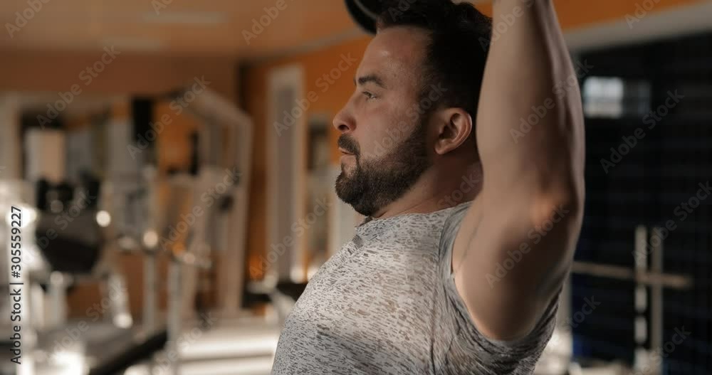 Man lifting dumbbells in a gym making exercise for deltoid muscles Man lifting dumbbells in a gym making exercise for deltoid muscles
